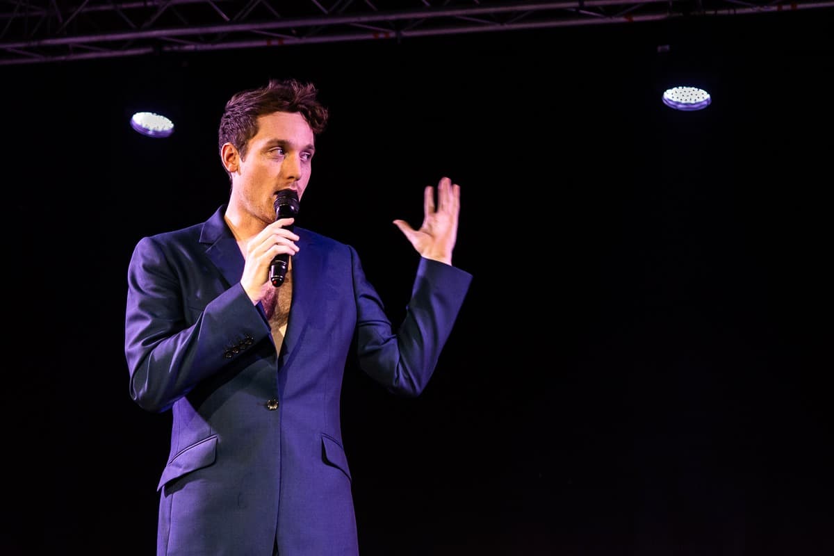 Christopher Adams on stage with a microphone