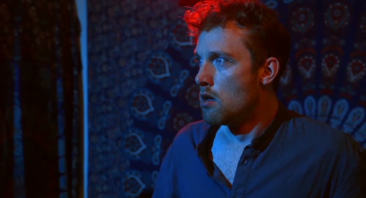 Christopher Adams lit blue, mouth open in alarm
