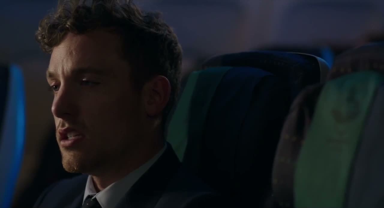 Christopher Adams in a suit in an aeroplane seat